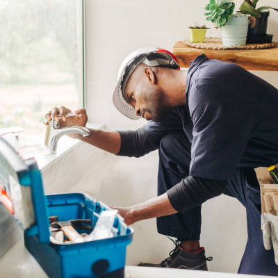Handyman repairing a tap fitting at a kitchen window