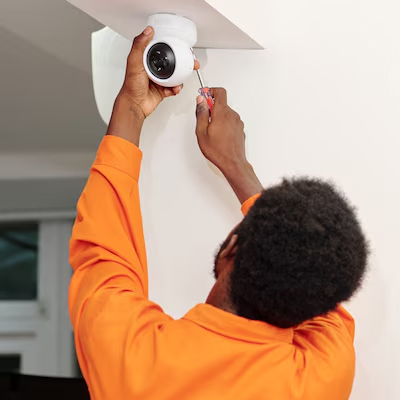Technician installing a CCTV security camera on a ceiling