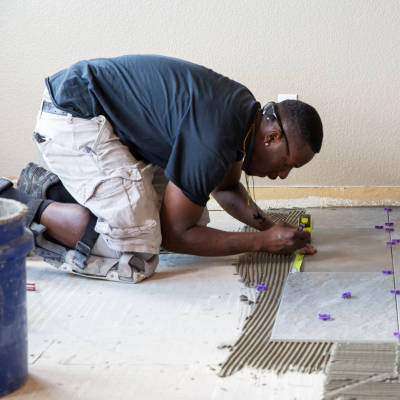 Tiler measuring and laying floor tiles